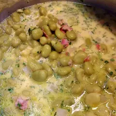 Dicke Bohnen werden in einer cremigen Sauce mit Speck und Kräutern zubereitet. Ein köstliches Gericht, das zum Genießen einlädt.