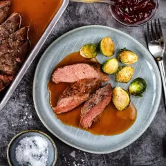Zart geschnittener Rehbraten in Rotwein-Sauce mit Rosenkohl. Ein Festmahl, das auf der Zunge zergeht.