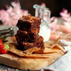 Gestapelte Brownies auf einem Holzbrett, daneben Erdbeeren. Ein tolles brownie rezept ohne schokolade für Naschkatzen.