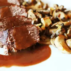 Geschnittenes Bratenfleisch mit Pilzen und einer dunklen Grundsauce.