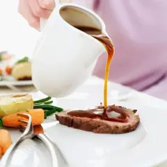 Eine Person übergießt ein Roastbeef mit Soße. Dazu gibt es Brokkoli, Karotten und Kartoffeln. Perfekt zum Fond kochen!