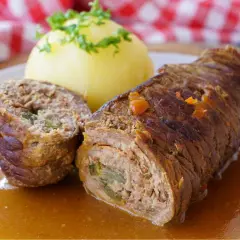 Saftige Rinderrouladen mit einer Füllung aus Hackfleisch und Gemüse, serviert mit Kartoffelklößen und einer köstlichen Soße.