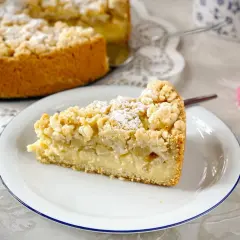 Ein Stück saftiger versunkener Apfelkuchen mit Pudding und Streuseln, bestäubt mit Puderzucker.
