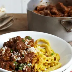Herzhaftes Gulasch mit Spätzle, das Fleisch wurde perfekt mariniert. Daneben ein Meerrettich und Besteck.