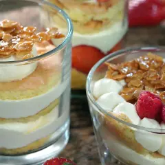 Schichten von Biskuit, Sahne und karamellisierten Mandeln, garniert mit Beeren. Ein köstlicher Bienenstich im Glas.