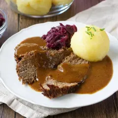Herzhaftes falsches Filet Sauerbraten mit Klößen und Rotkohl, übergossen mit dunkler Soße.