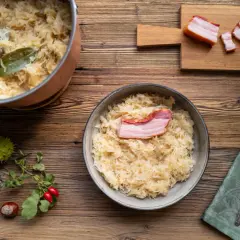 Herzhaftes Sauerkraut mit Speck, perfekt für ein Oktoberfest-Rezept. Ein Topf mit Sauerkraut und ein Teller mit dem fertigen Gericht stehen bereit.