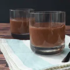 Zwei Gläser cremiger Schokopudding, selbstgemacht mit Kakao. Ein Löffel liegt bereit für den Genuss.