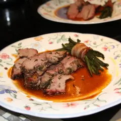 Zarte Lammfleischscheiben mit Kräutern, serviert mit Speck-umwickelten grünen Bohnen und einer köstlichen Sauce zu Lamm.