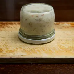 Glas mit Griebenschmalz, bereit für das Griebenschmalz Rezept. Auf einem Holzbrett.