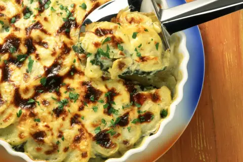 Herzhaftes Mangold-Kartoffel-Gratin mit goldbrauner Käsekruste, garniert mit frischer Petersilie. Ein köstliches Rezept!