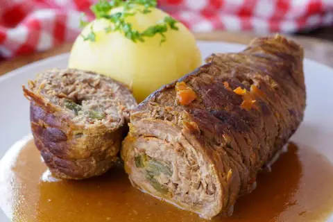 Saftige Rinderrouladen mit einer Füllung aus Hackfleisch und Gemüse, serviert mit Kartoffelklößen und einer köstlichen Soße.