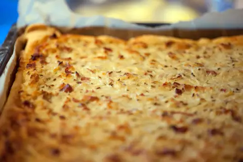 Frisch gebackener Zwiebelkuchen im Blech, ein köstliches zwiebelkuchen originalrezept mit Speck und Kümmel.