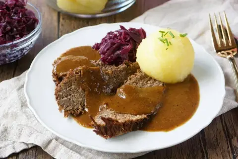 Herzhaftes falsches Filet Sauerbraten mit Klößen und Rotkohl, übergossen mit dunkler Soße.