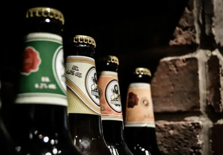 Mehrere Bierflaschen stehen nebeneinander, bereit zum Bier lagern. Die Etiketten zeigen verschiedene Designs und Alkoholprozente.