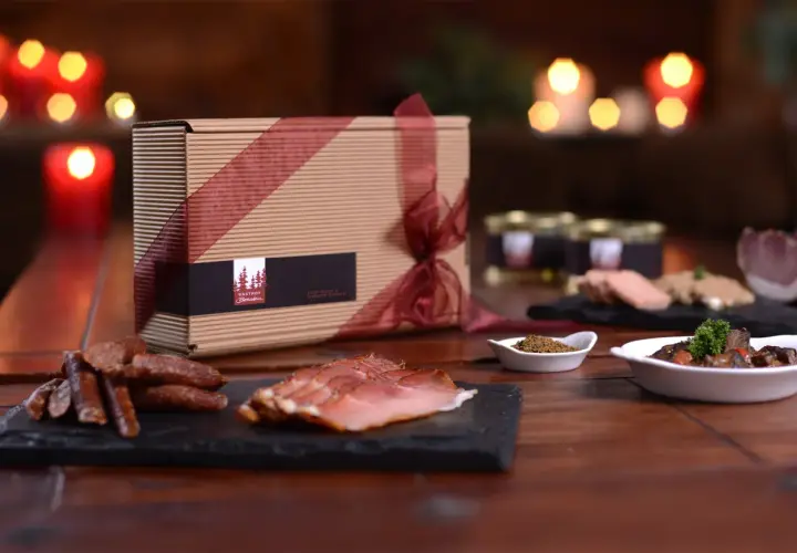 Geschenkbox mit Wurstwaren und Pastete, dazu ein Glas mit Gewürzen und ein Gericht mit Fleisch. Perfekt zu einem Glas **amber ale**.