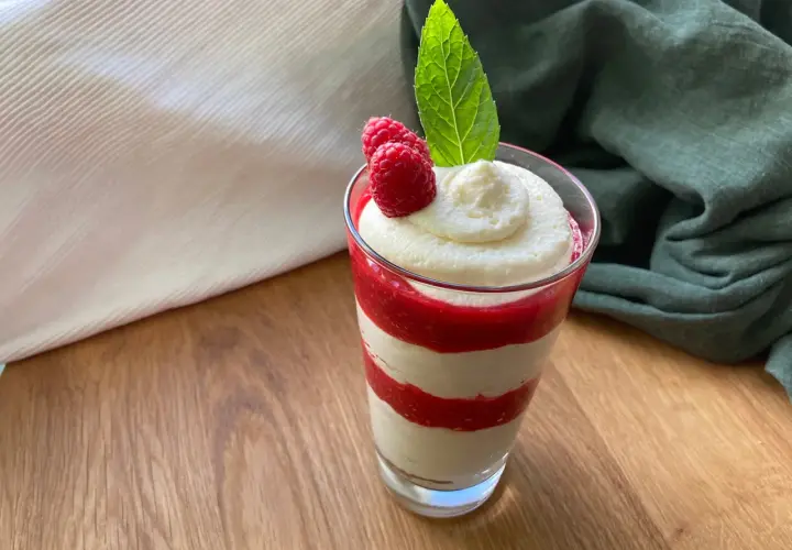 Schichtdessert im Glas mit Himbeersoße und einfacher Schmandcreme, garniert mit frischen Himbeeren und Minze.