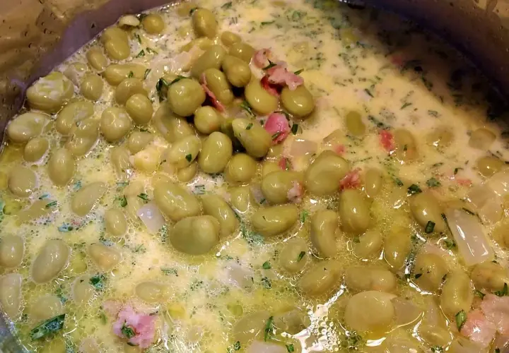 Dicke Bohnen werden in einer cremigen Sauce mit Speck und Kräutern zubereitet. Ein köstliches Gericht, das zum Genießen einlädt.