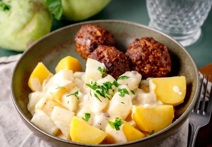 Herzhafte Frikadellen mit Kartoffeln und Kohlrabi in cremiger Sahnesauce, garniert mit Petersilie.