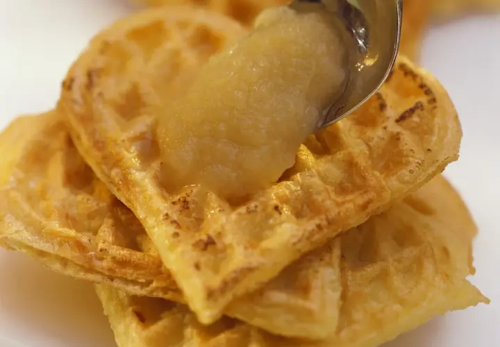Goldbraune Waffeln, gestapelt und mit einem Löffel Apfelmus bedeckt. Ein süßer Genuss!