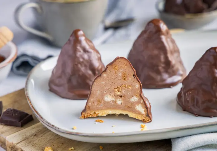 Schokoladen-Desserts, die an Granatsplitter erinnern, auf einem Teller. Ein Stück ist angeschnitten und zeigt die cremige Füllung mit Keksstückchen. Ein tolles granatsplitter rezept.