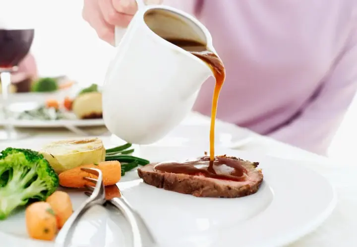 Eine Person übergießt ein Roastbeef mit Soße. Dazu gibt es Brokkoli, Karotten und Kartoffeln. Perfekt zum Fond kochen!