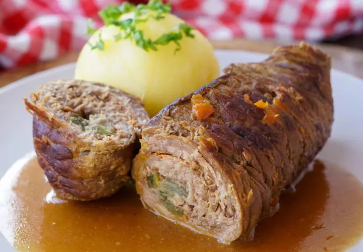 Saftige Rinderrouladen mit einer Füllung aus Hackfleisch und Gemüse, serviert mit Kartoffelklößen und einer köstlichen Soße.