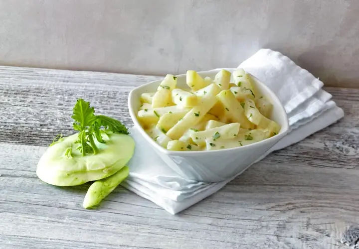 Kohlrabi in cremiger Sauce, bereit für die Kochzeit. Daneben ein frischer Kohlrabi mit Grün.