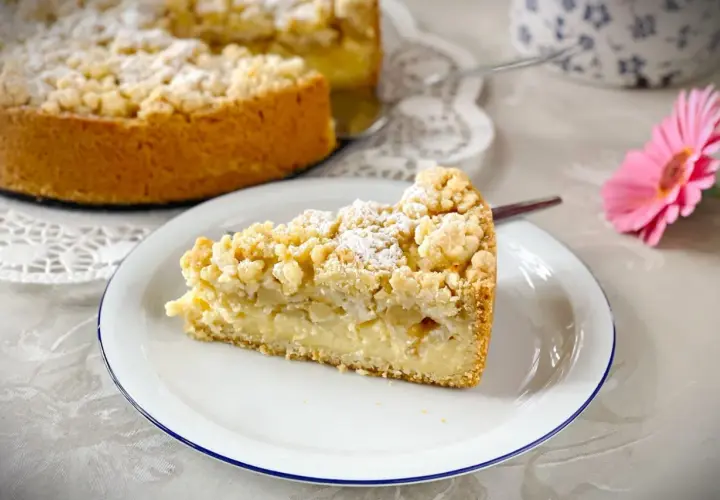 Ein Stück saftiger versunkener Apfelkuchen mit Pudding und Streuseln, bestäubt mit Puderzucker.