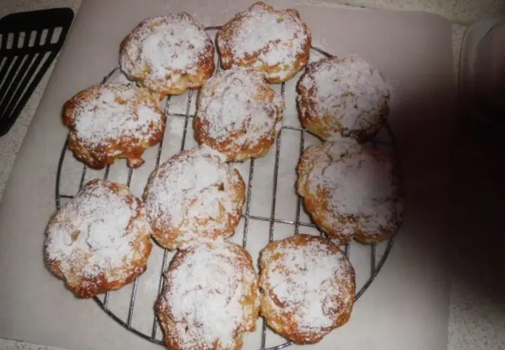 Saftige Apfeltaler mit Quark, bestäubt mit Puderzucker, auf einem Kuchengitter.