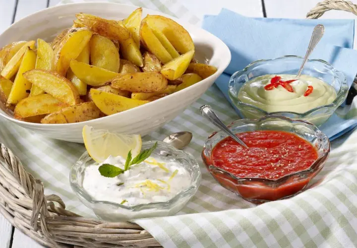Knusprige Kartoffelecken mit drei Dips: ein cremiger Dip mit Chili, ein roter Dip und ein Joghurt-Dip mit Zitrone und Minze. Perfekt zum Teilen!