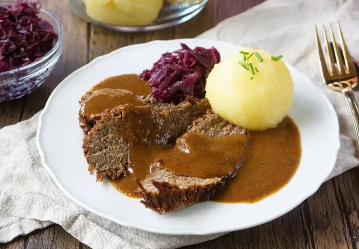 Herzhaftes falsches Filet Sauerbraten mit Klößen und Rotkohl, übergossen mit dunkler Soße.