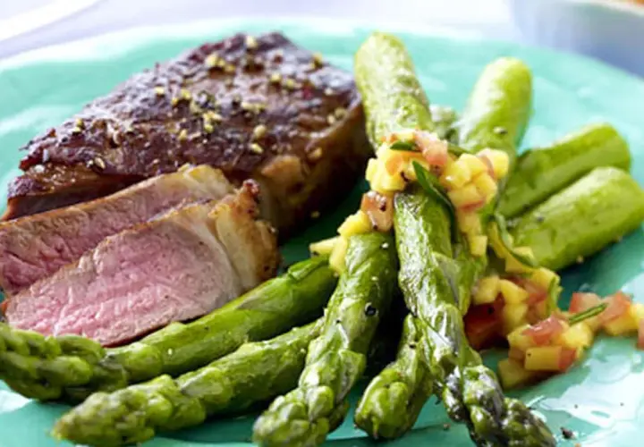 Saftiger Rumpsteak in der Pfanne, medium gebraten, serviert mit grünem Spargel und einer fruchtigen Salsa.