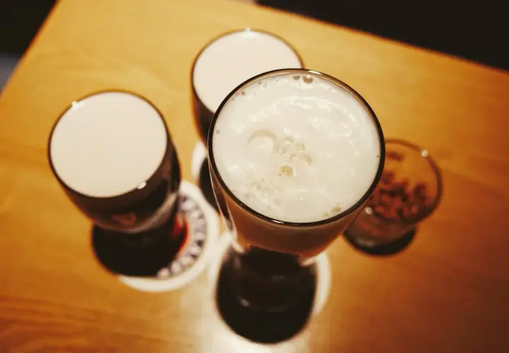 Drei Gläser mit Schaumkrone und ein Glas mit Nüssen – perfekte blindverkostung ideen für einen gemütlichen Abend.