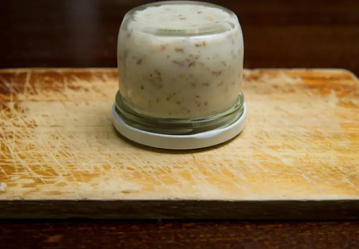 Glas mit Griebenschmalz, bereit für das Griebenschmalz Rezept. Auf einem Holzbrett.