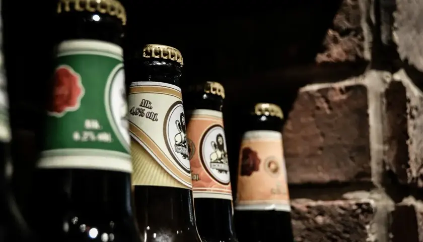 Mehrere Bierflaschen stehen nebeneinander, bereit zum Bier lagern. Die Etiketten zeigen verschiedene Designs und Alkoholprozente.