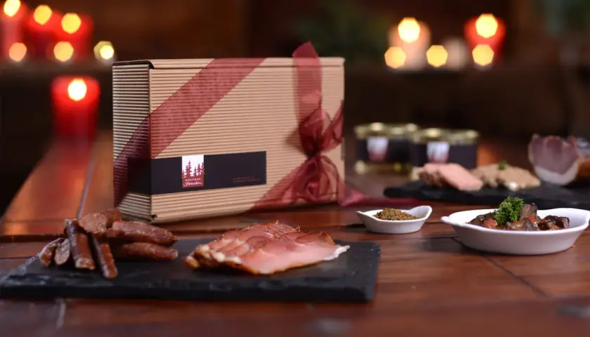 Geschenkbox mit Wurstwaren und Pastete, dazu ein Glas mit Gewürzen und ein Gericht mit Fleisch. Perfekt zu einem Glas **amber ale**.