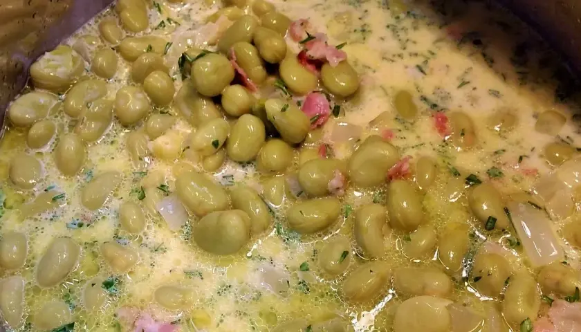 Dicke Bohnen werden in einer cremigen Sauce mit Speck und Kräutern zubereitet. Ein köstliches Gericht, das zum Genießen einlädt.