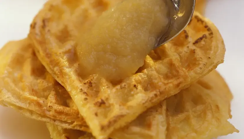 Goldbraune Waffeln, gestapelt und mit einem Löffel Apfelmus bedeckt. Ein süßer Genuss!