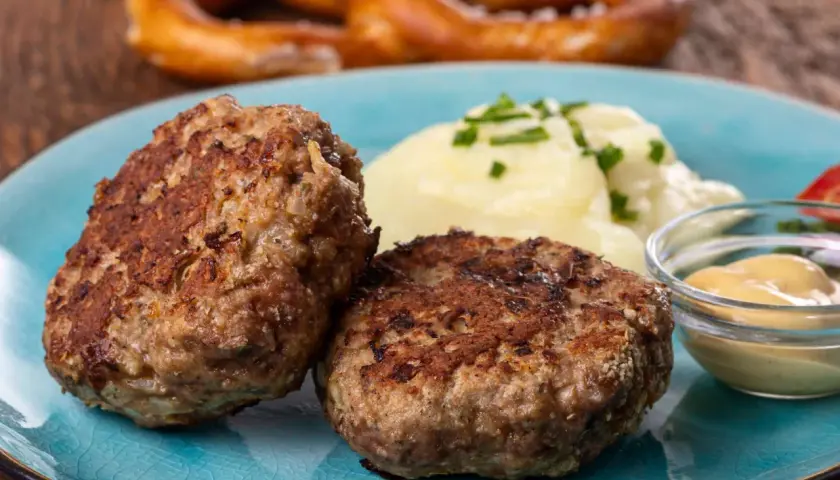 Zwei goldbraune Frikadellen mit Kartoffelbrei und Senf. Dieses Gericht ist ein Beweis für das beste Frikadellen Rezept, das man sich wünschen kann.