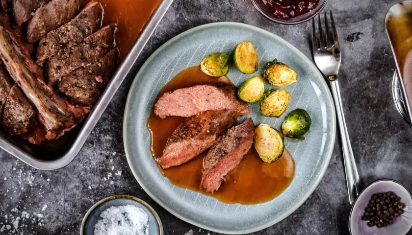 Zart geschnittener Rehbraten in Rotwein-Sauce mit Rosenkohl. Ein Festmahl, das auf der Zunge zergeht.