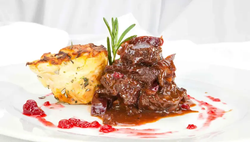 Deftiges Gulasch mit Preiselbeeren und Kartoffelgratin. Einfache reh rezepte für ein festliches Essen.