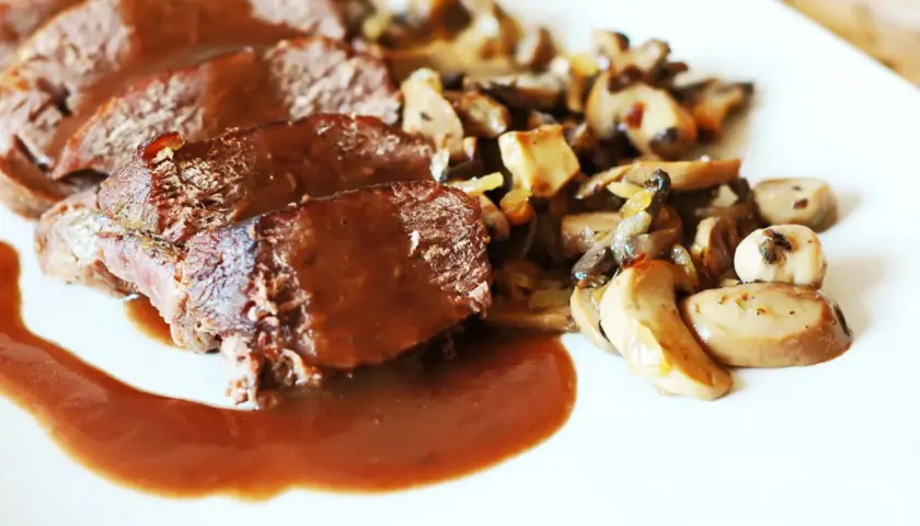 Geschnittenes Bratenfleisch mit Pilzen und einer dunklen Grundsauce.