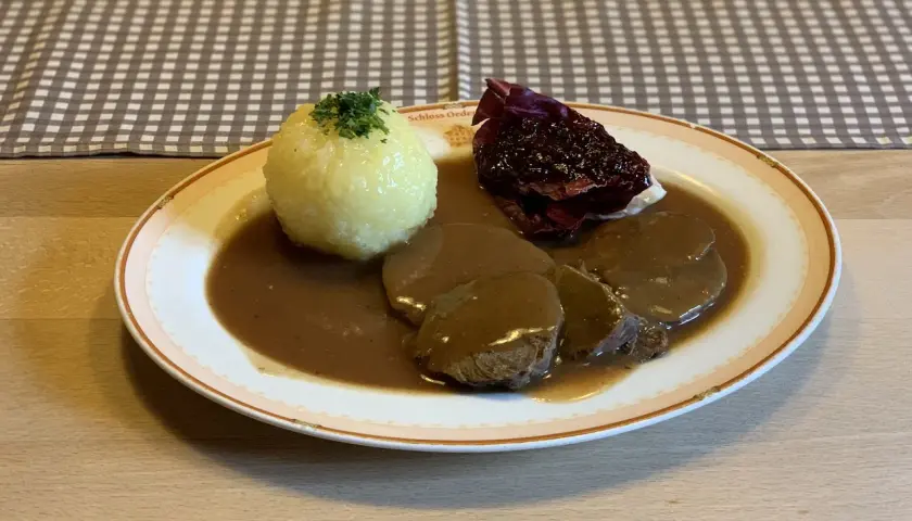 Deftig geschmortes Rindfleisch in dunkler Sauce mit Klößen und Rotkohl. Ein Klassiker, der an Omas **Treber Rezepte** erinnert.