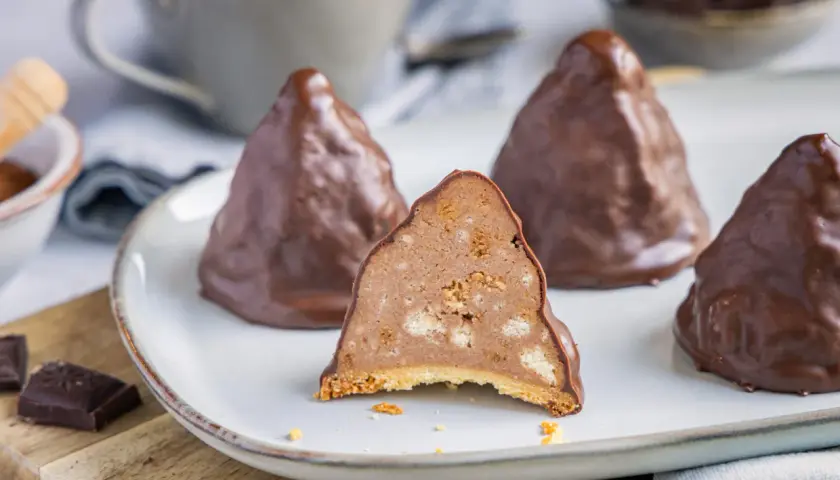 Schokoladen-Desserts, die an Granatsplitter erinnern, auf einem Teller. Ein Stück ist angeschnitten und zeigt die cremige Füllung mit Keksstückchen. Ein tolles granatsplitter rezept.