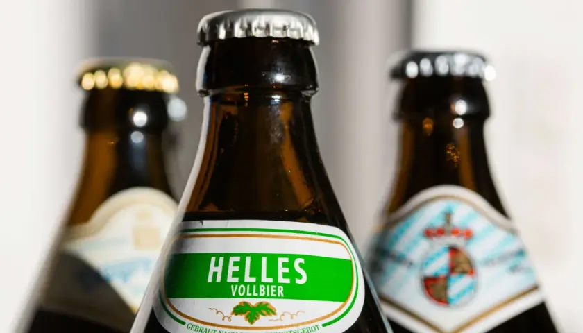 Drei Bierflaschen, eine mit "Helles Vollbier" beschriftet. Der Unterschied zwischen Vollbier und hellem Bier wird hier visuell angedeutet.