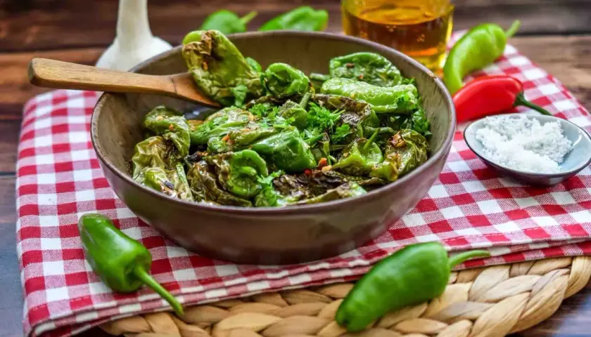 Gebratene Pimientos de Padrón, ein einfaches und leckeres Rezept. Mit grobem Salz bestreut, serviert mit Olivenöl und frischen Kräutern.