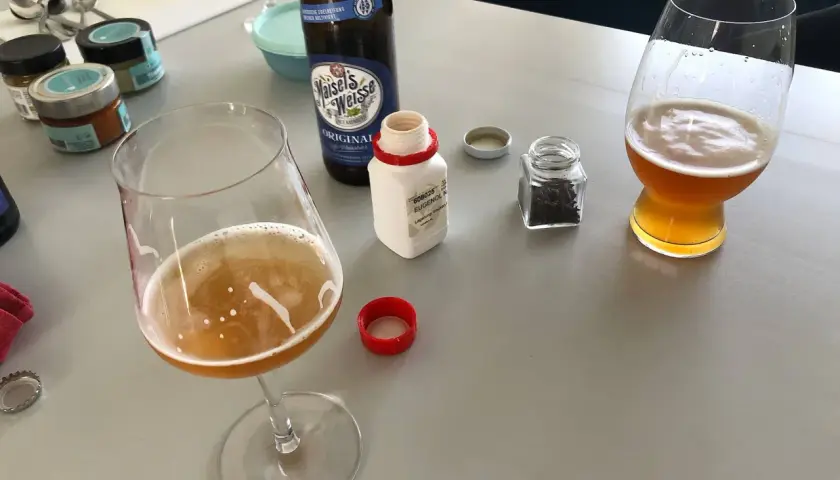 Zwei Gläser Weizenbier, eine Flasche Maisel's Weisse und kleine Gläser mit Gewürzen. Der Weizenbier Geschmack wird durch die Zutaten verfeinert.