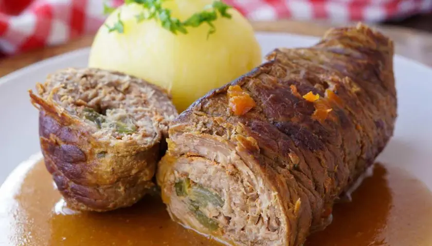 Saftige Rinderrouladen mit einer Füllung aus Hackfleisch und Gemüse, serviert mit Kartoffelklößen und einer köstlichen Soße.