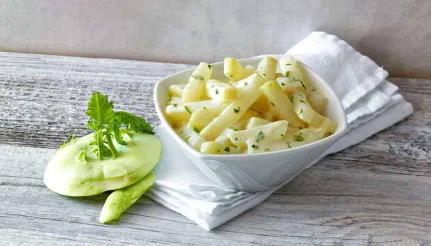 Kohlrabi in cremiger Sauce, bereit für die Kochzeit. Daneben ein frischer Kohlrabi mit Grün.